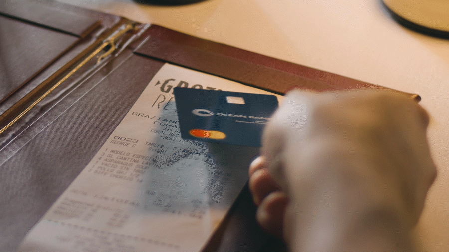 A person paying a restaurant check with the Ocean Card Business Rewards Preferred
